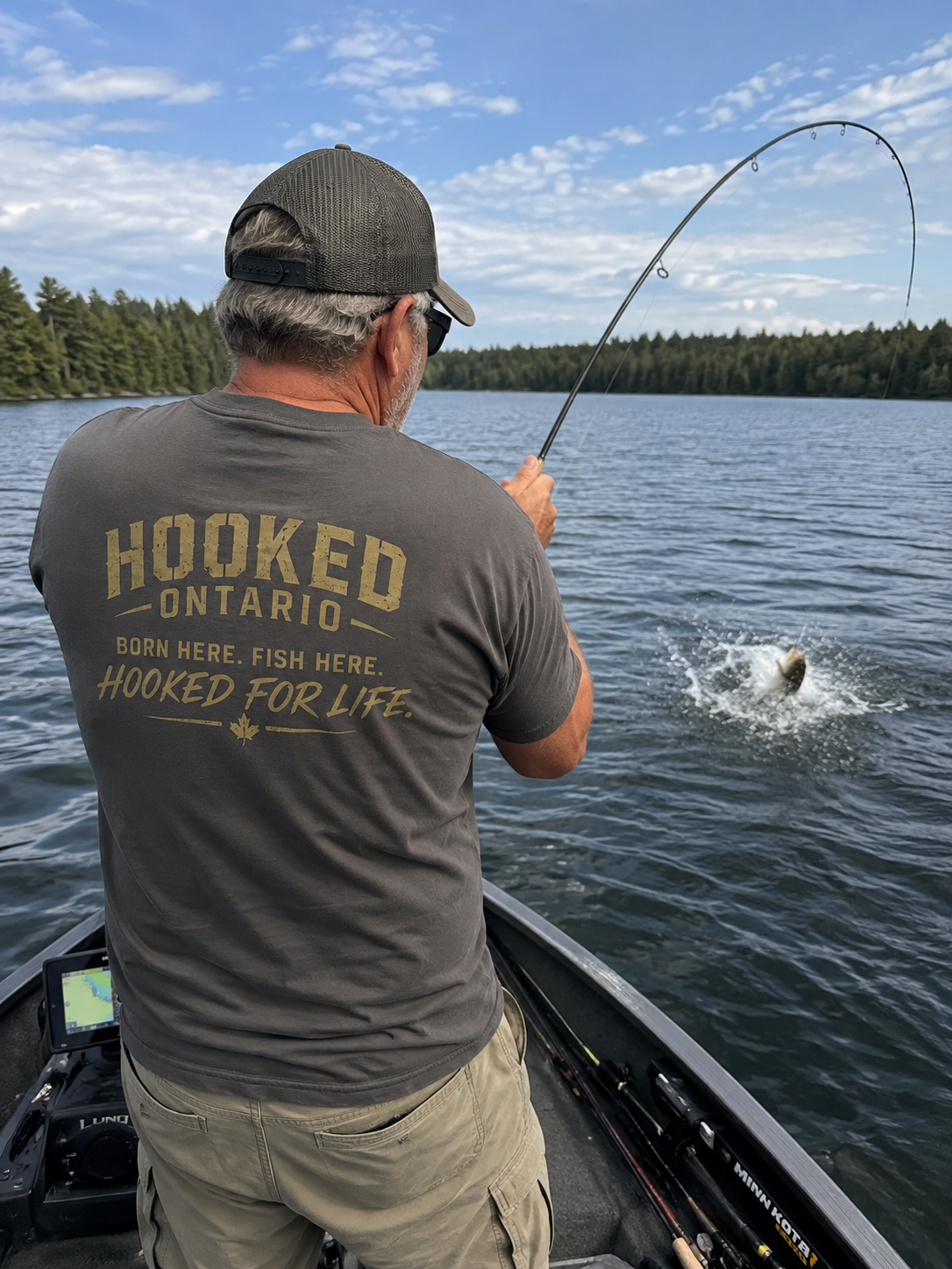 Angler in a Hooked Ontario 'Born Here. Fish Here.' tee fighting a fish from a boat